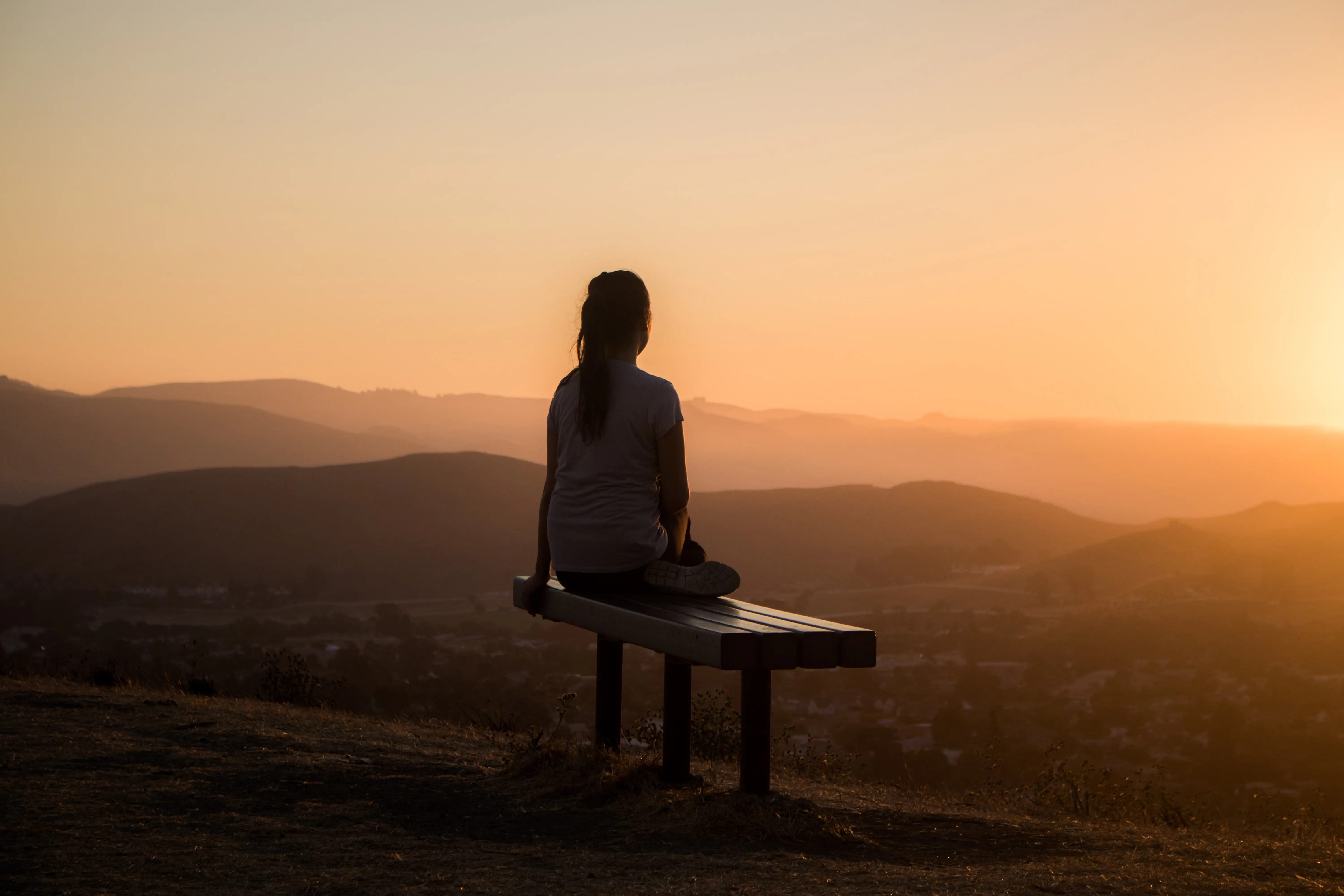 Women sitting on a bench meditating at sunrise