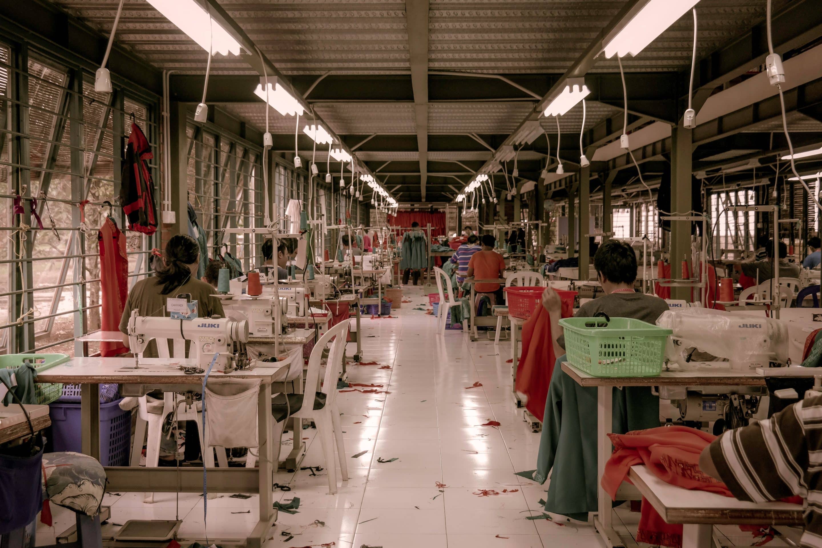 image of a factory floor with long rows of tables set up for sewing machines